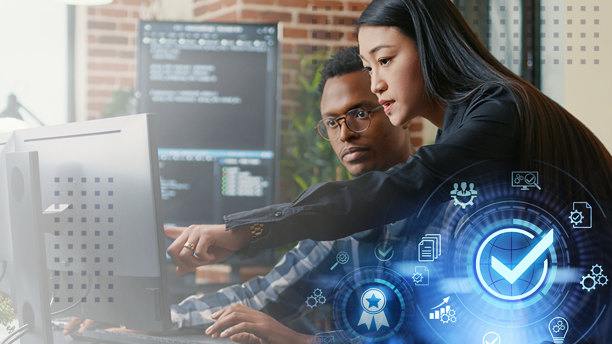 A female coworker standing  and pointing to a computer monitor over her male coworker with an abstract check mark symbol overlay