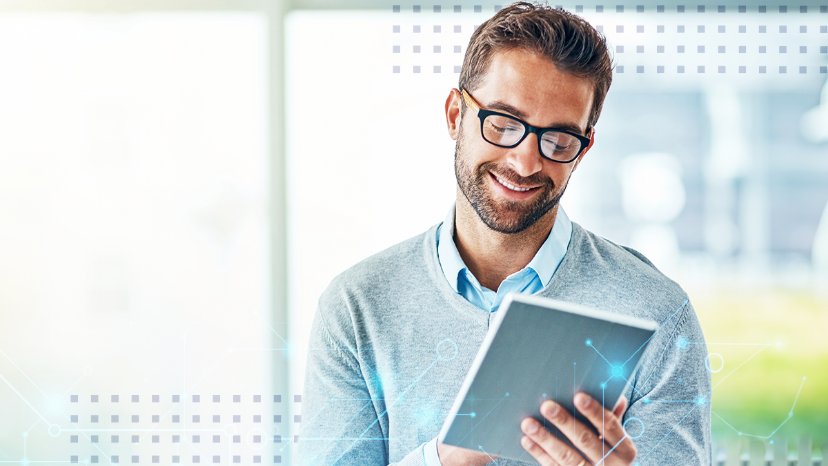 A man with glasses smiling while looking at a tablet