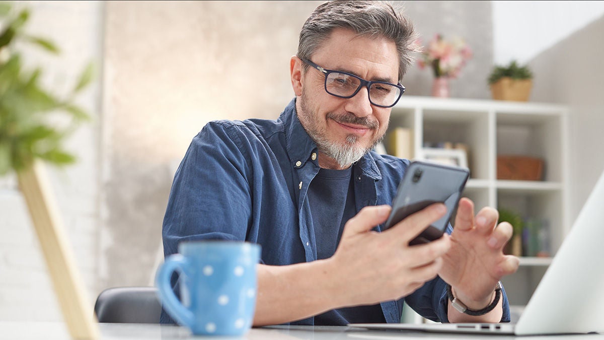 Smliing man reading on device