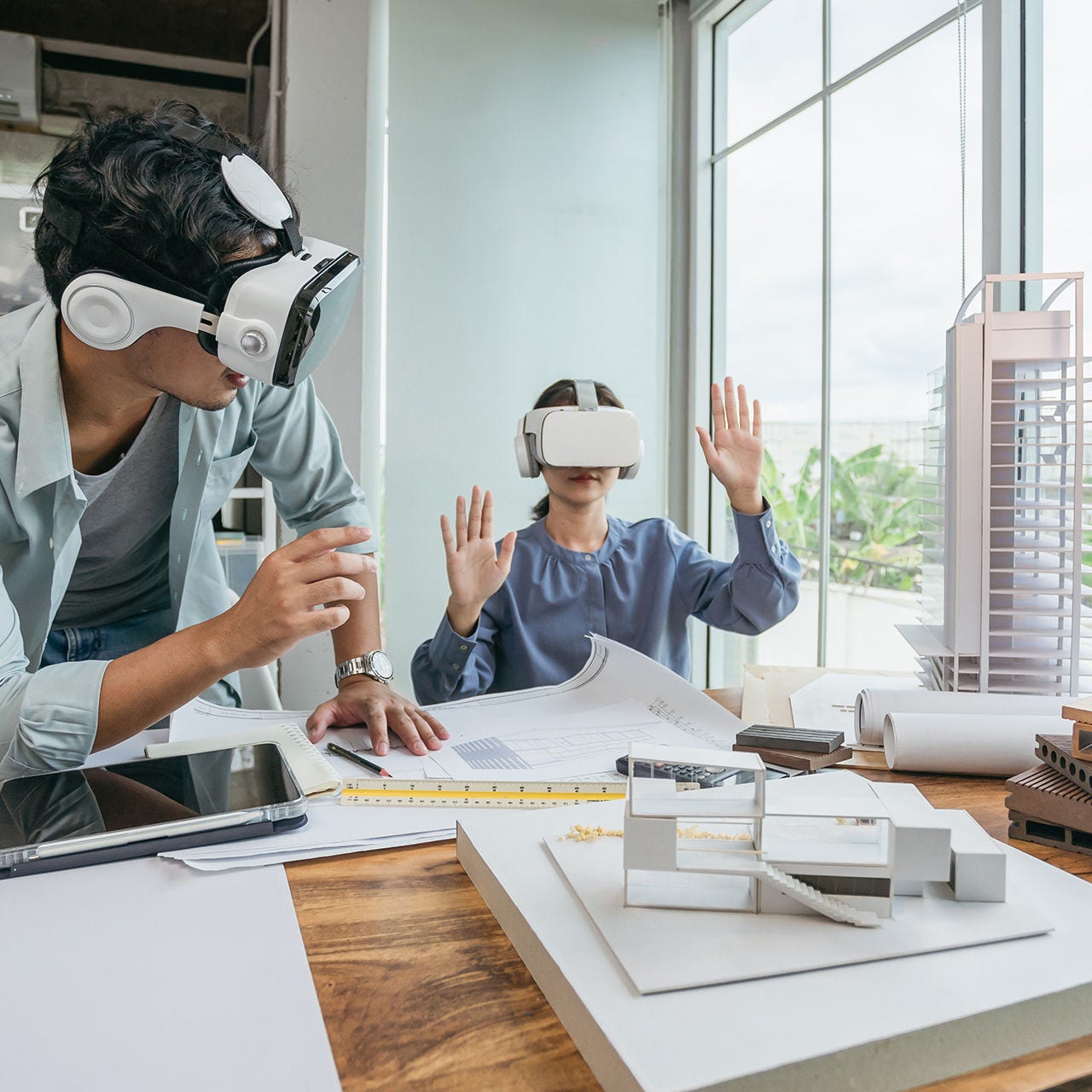 Two coworkers at a desk using VR goggles powered by 50G-PON to view an architecture project