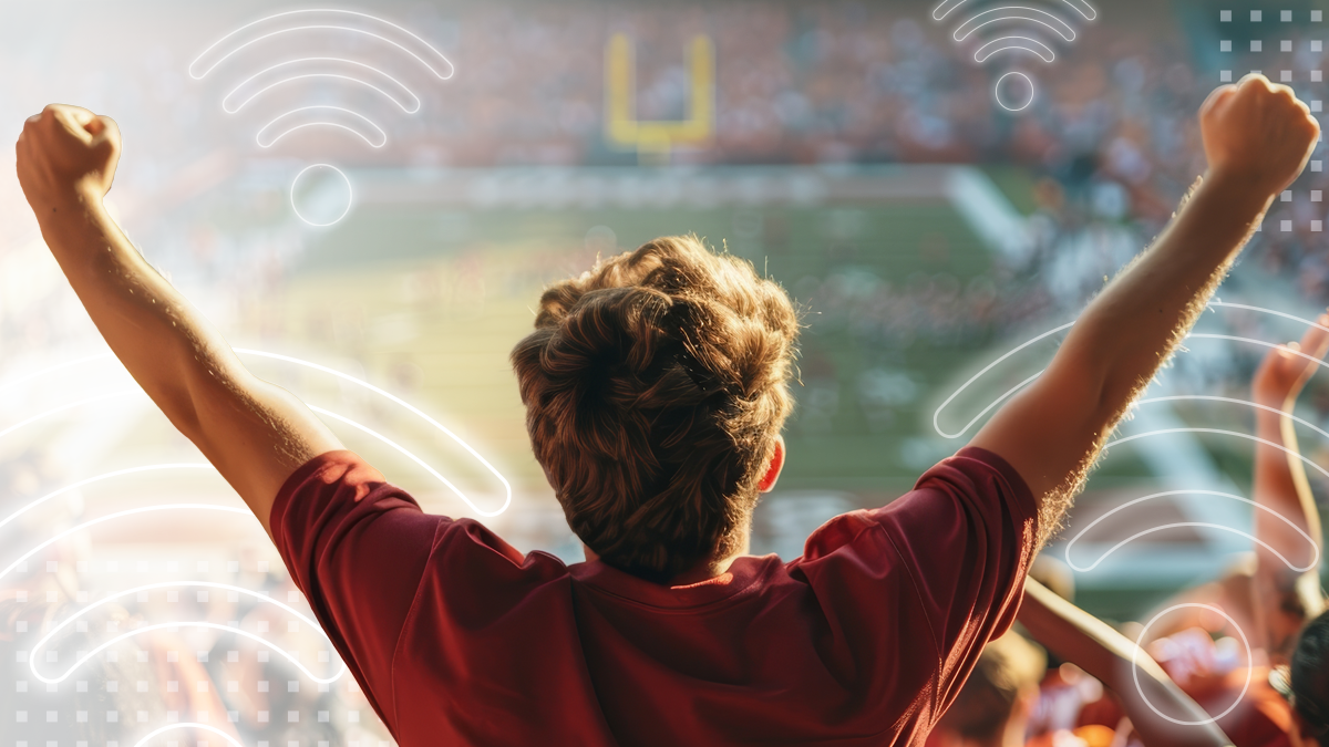 A man in red t-shirt is standing in stadium full of people celebrating a goal or victory