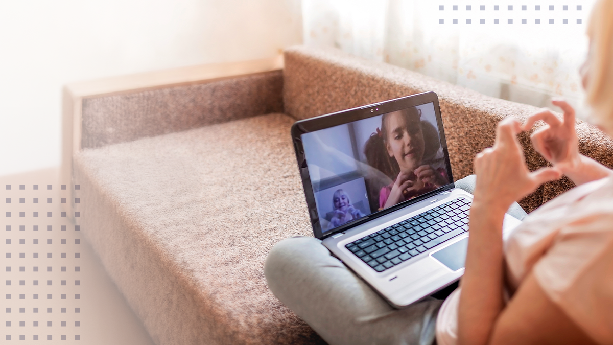 A woman sitting on a couch in a video chat with a young child on her laptop