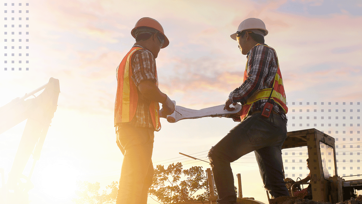 Two workers outside looking at construction blueprints