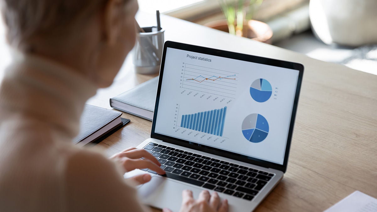 Worker looking at laptop with growth graph on screen