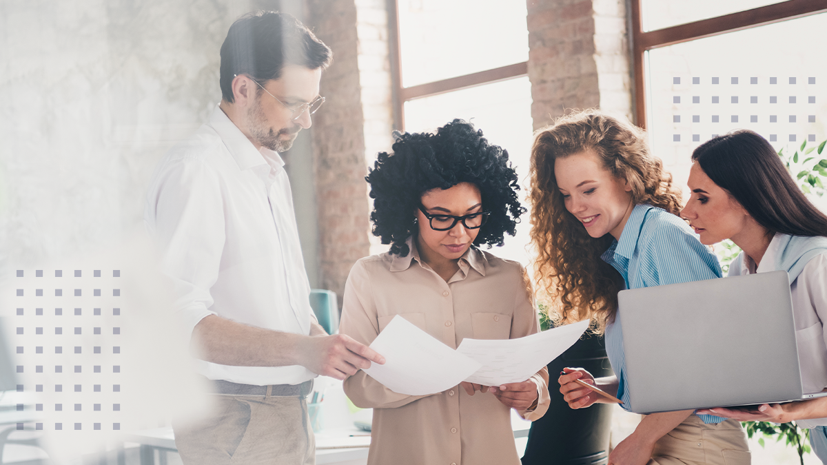 A group of male and female coworkers looking over each other at paper documents