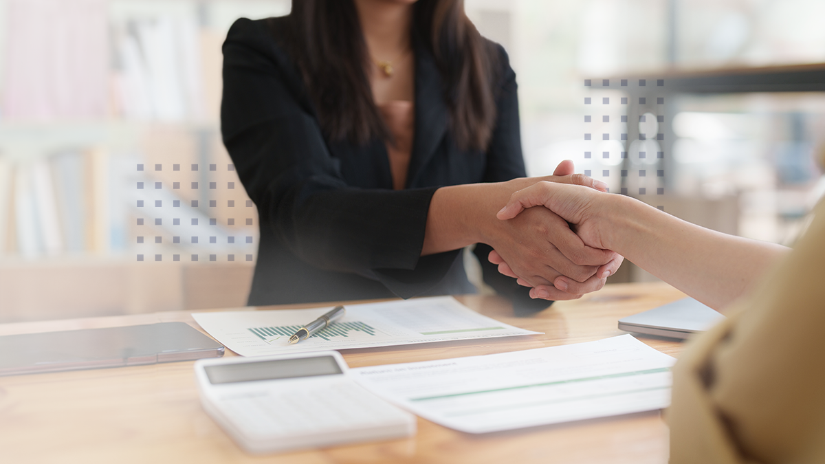 A business woman at a desk shaking hands with a BEAD funding applicant