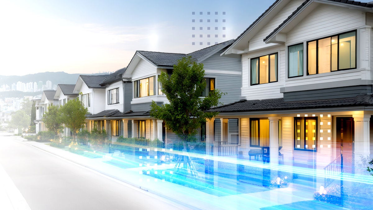 A row of modern suburban houses lines a quiet residential street. The homes feature clean white facades, large windows, and small trees in front yards. Bright blue and white light trails run along the street, suggesting high-speed data or futuristic connectivity. Warm interior lighting contrasts with the cool exterior tones, creating a blend of technology and comfortable neighborhood living.
