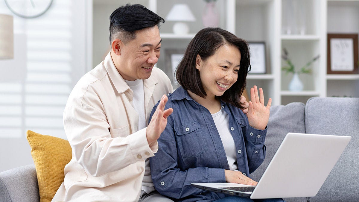 Happy couple waving into laptop