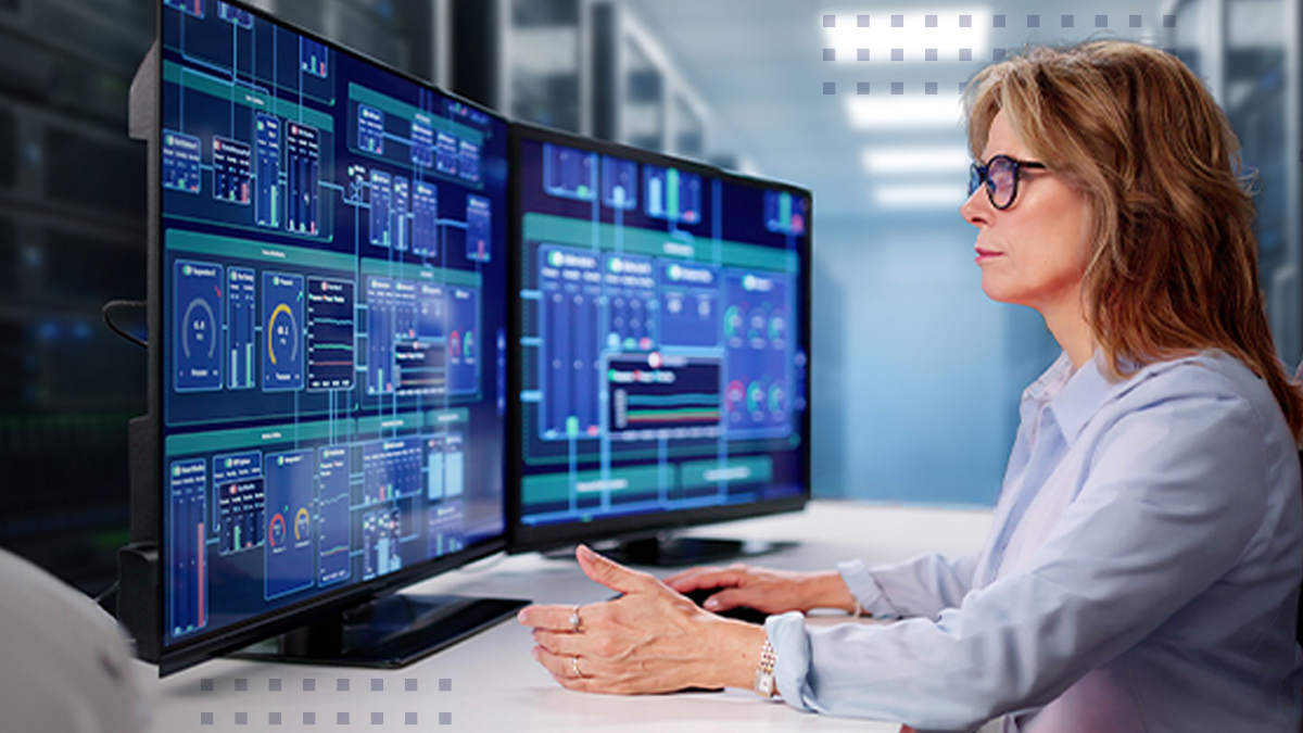 A woman looking at computer monitors that display analytical data and graphs