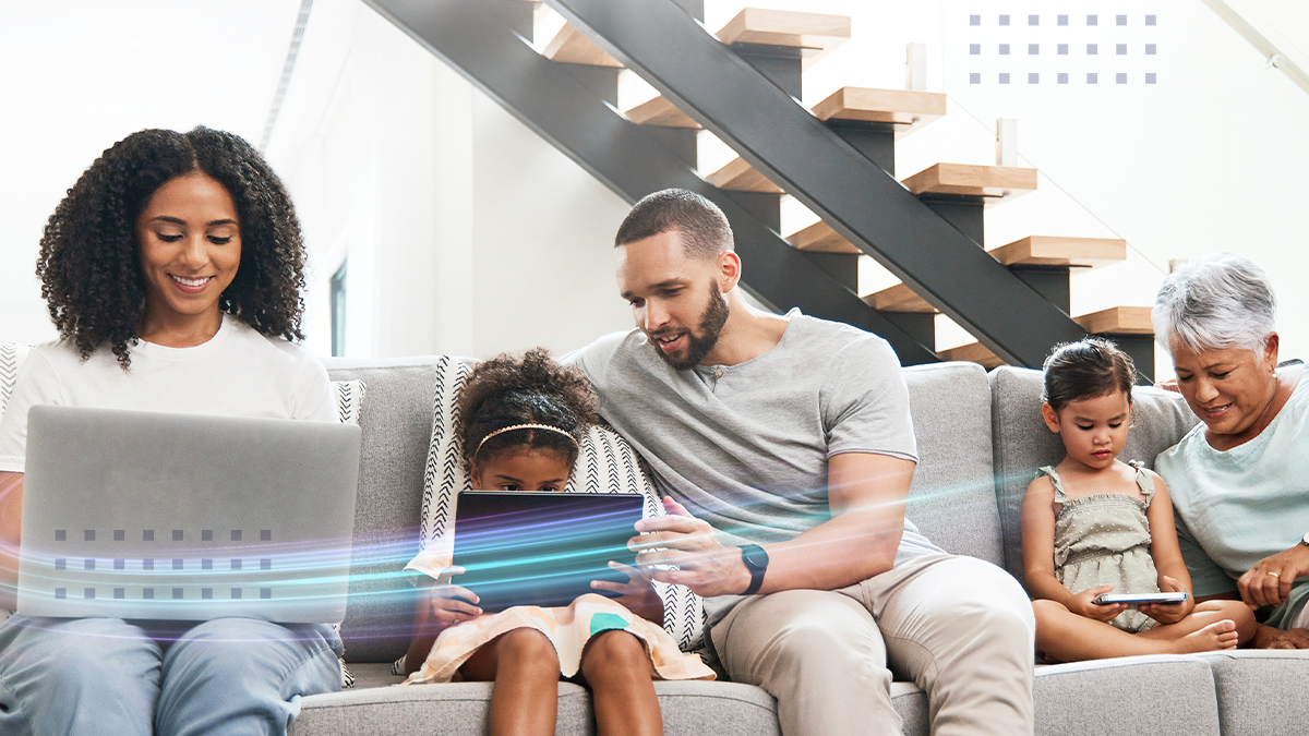 A family sitting on a couch uwith various electronic devices using a Calix Gigapoint Optical Network Terminal (ONT) for Gigabit broadband service