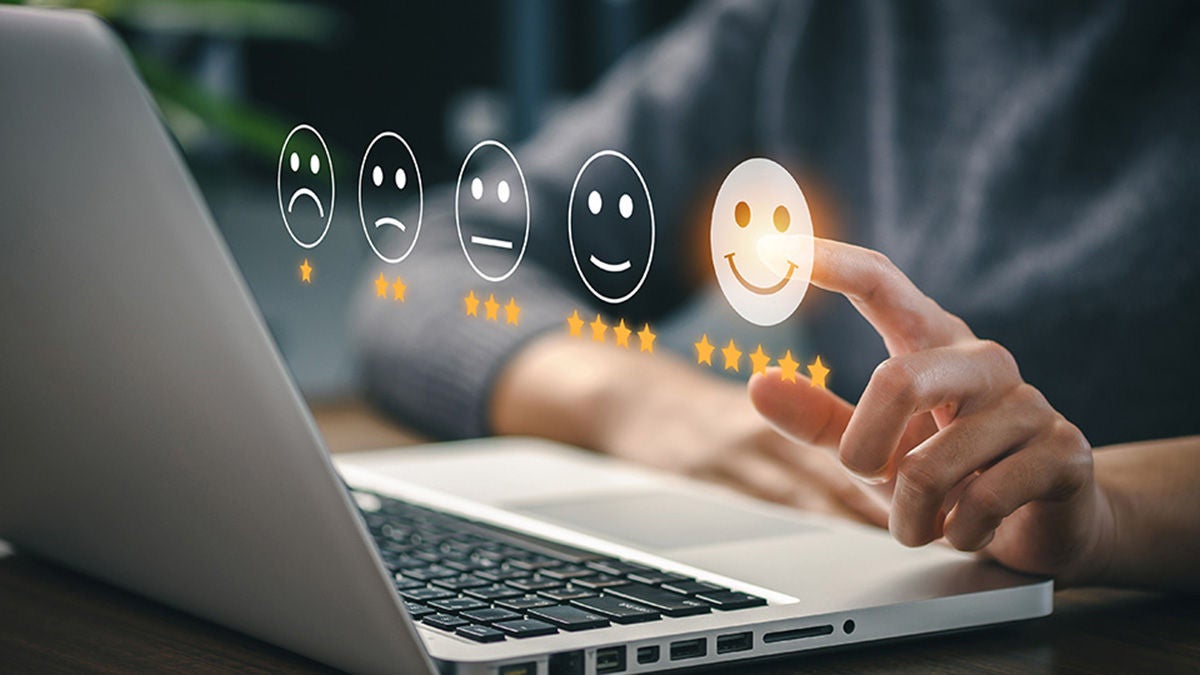 Person selects a five-star happy face on a laptop screen, representing positive feedback and excellent user experience