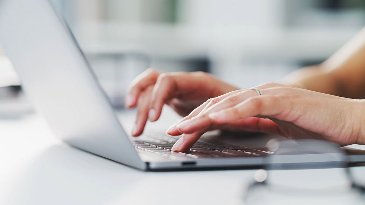 Female hands typing on a laptop keyboard on a table