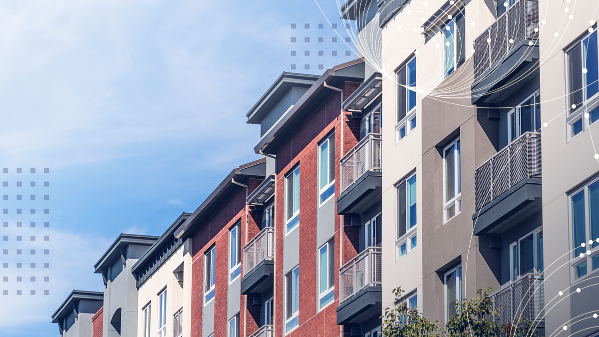 A row of contemporary apartment buildings is shown under a blue sky, featuring a mix of red and neutral facades with balconies