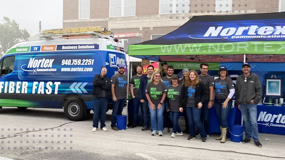 A group of Nortex employees posing for a photo outside next to a work van and large canopy