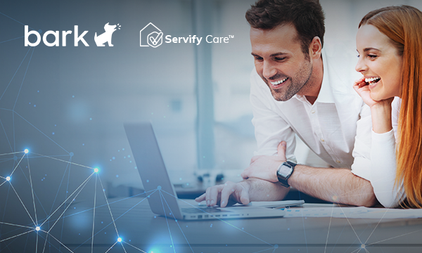 smiling man and a woman looking at a laptop screen in a modern office space